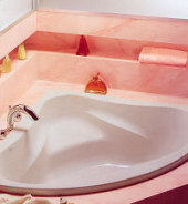 Eckbadewanne in rosa-marmorierter Einfassung